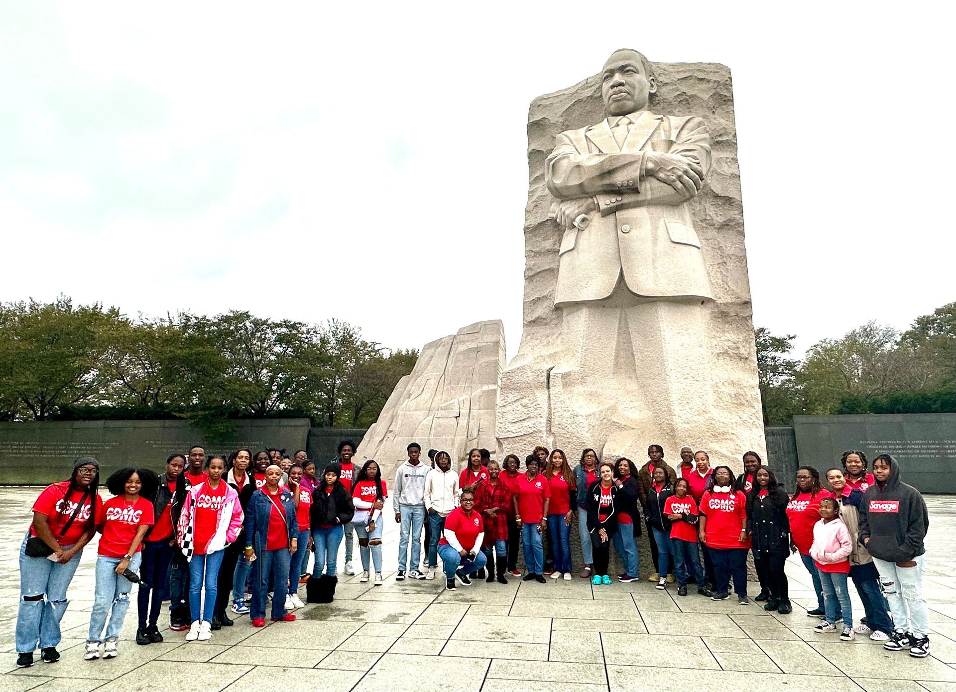 Group of people in red shirts pose in front of the Martin Luther King Jr. Memorial.