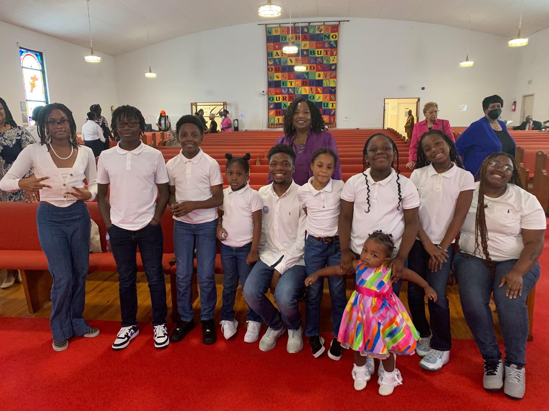 Group of people posing in a church with red carpet. Several children and an adult in the center.