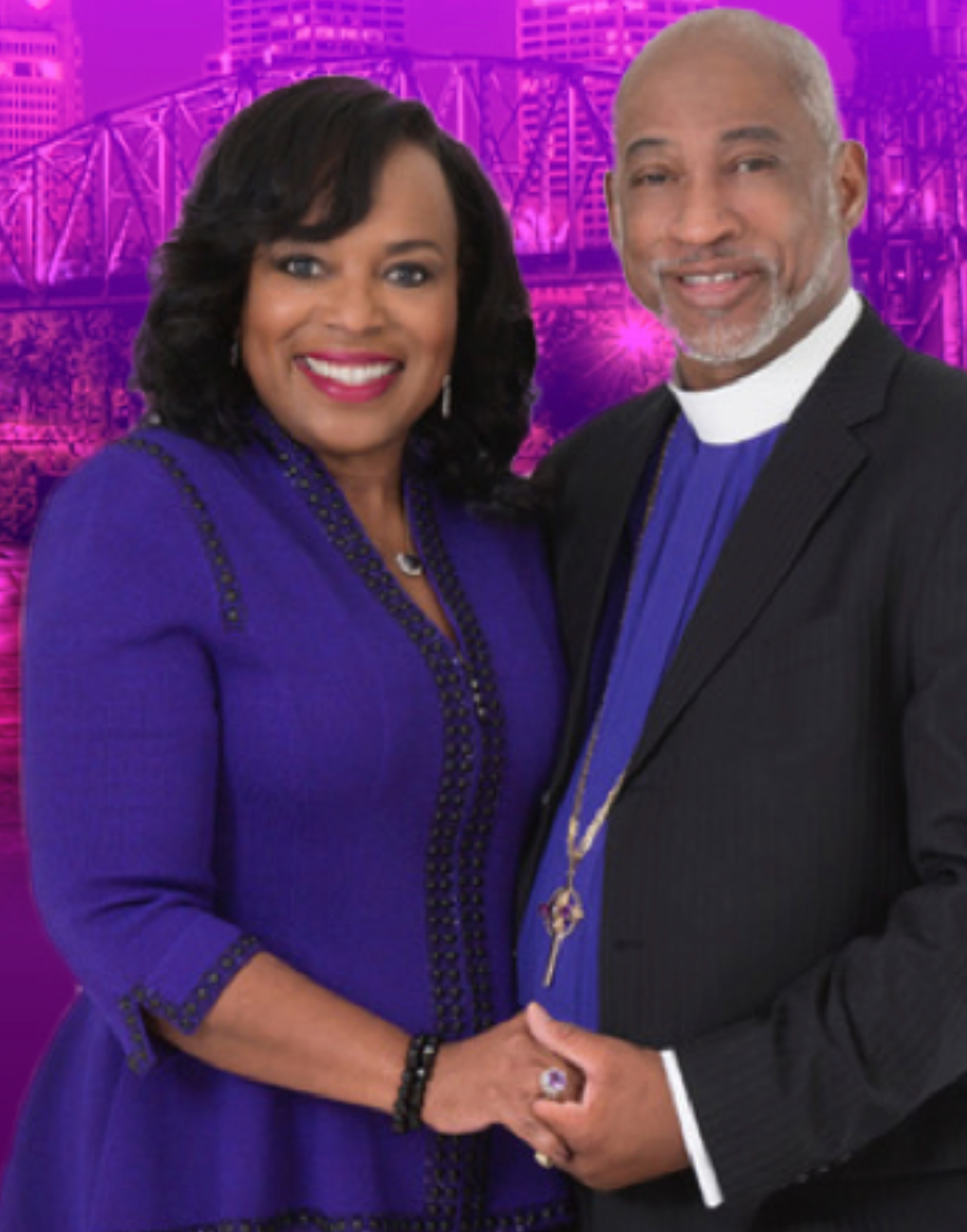 Couple in formal attire, holding hands, smiling. Purple background with city silhouette.
