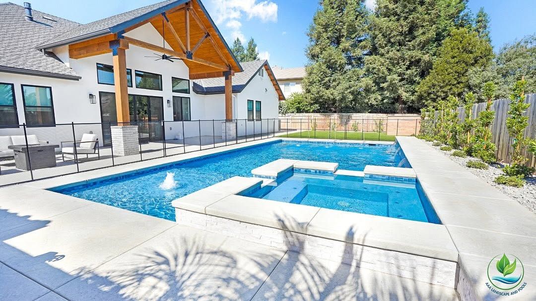Modern backyard with a blue swimming pool, white patio, and covered seating area beside a house.