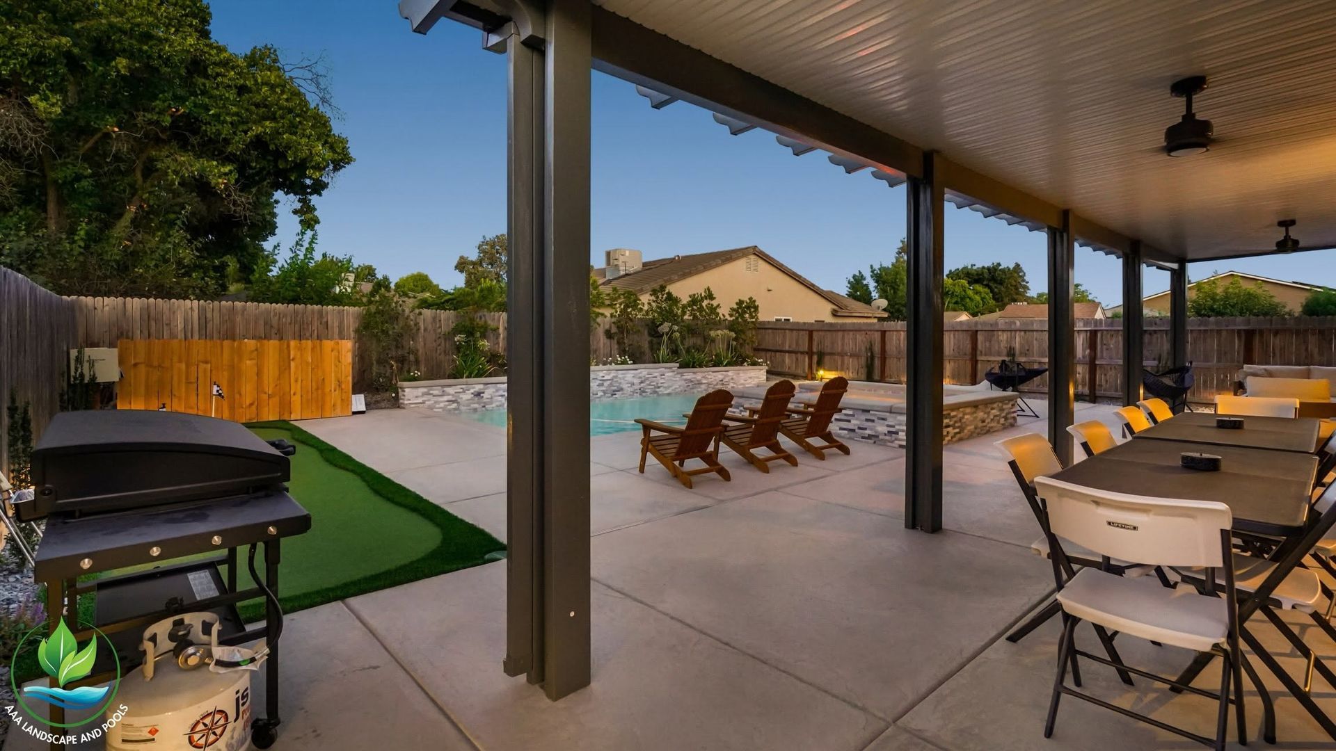 Covered patio with outdoor dining tables, lounge chairs, grill, and a swimming pool in the background