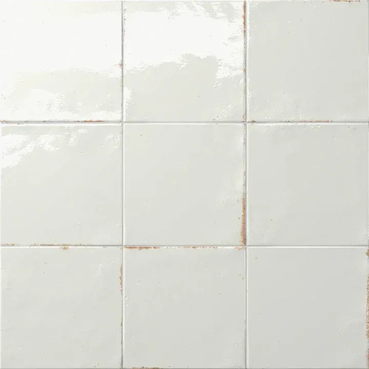 White ceramic wall tiles with subtle grout lines and light discoloration