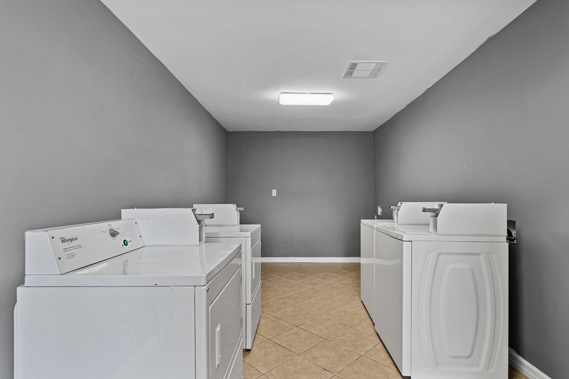 Laundry room with two white washing machines and gray walls in a narrow utility space