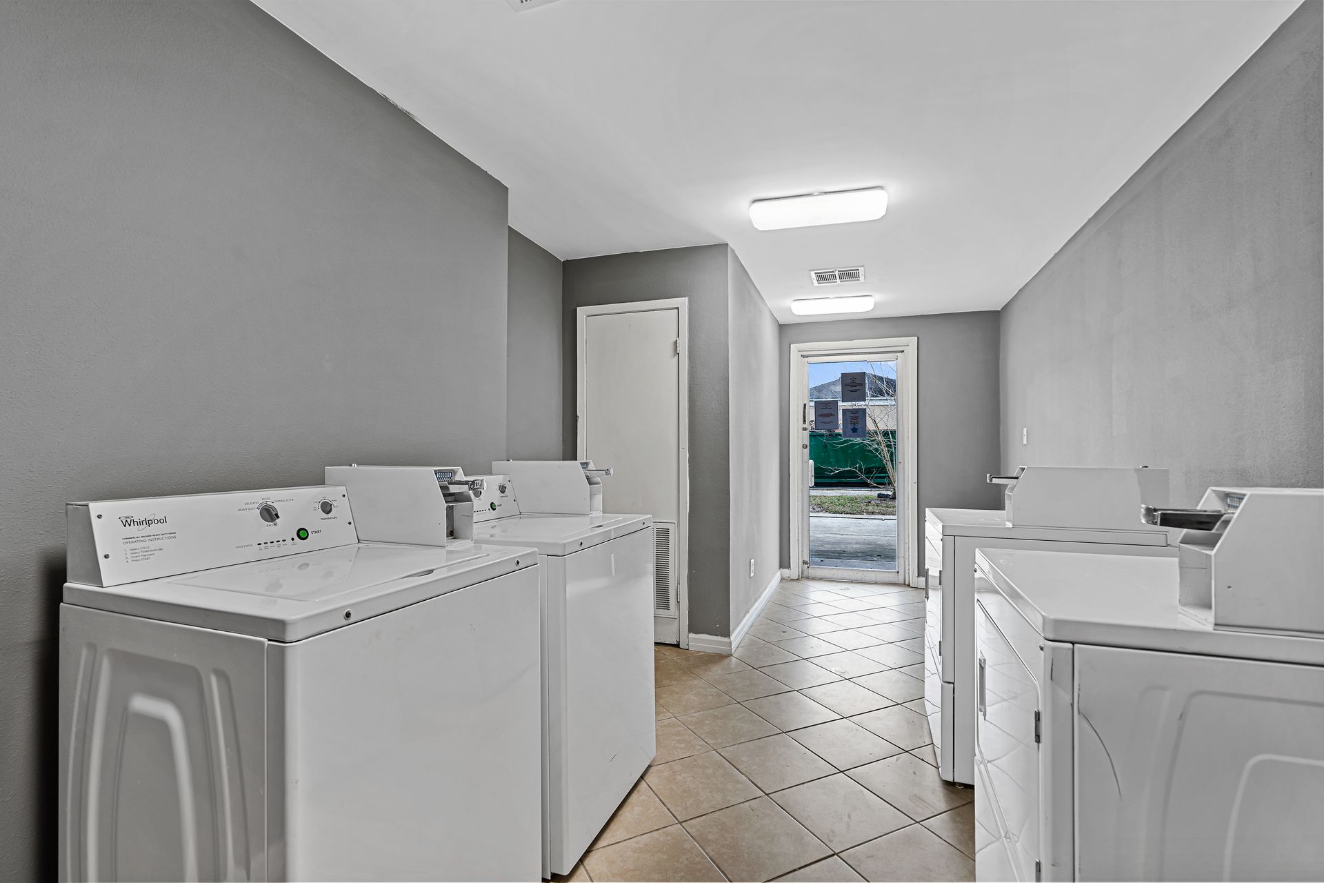 Laundry room with washer and dryer on both sides, tiled floor, and a door to the outside.