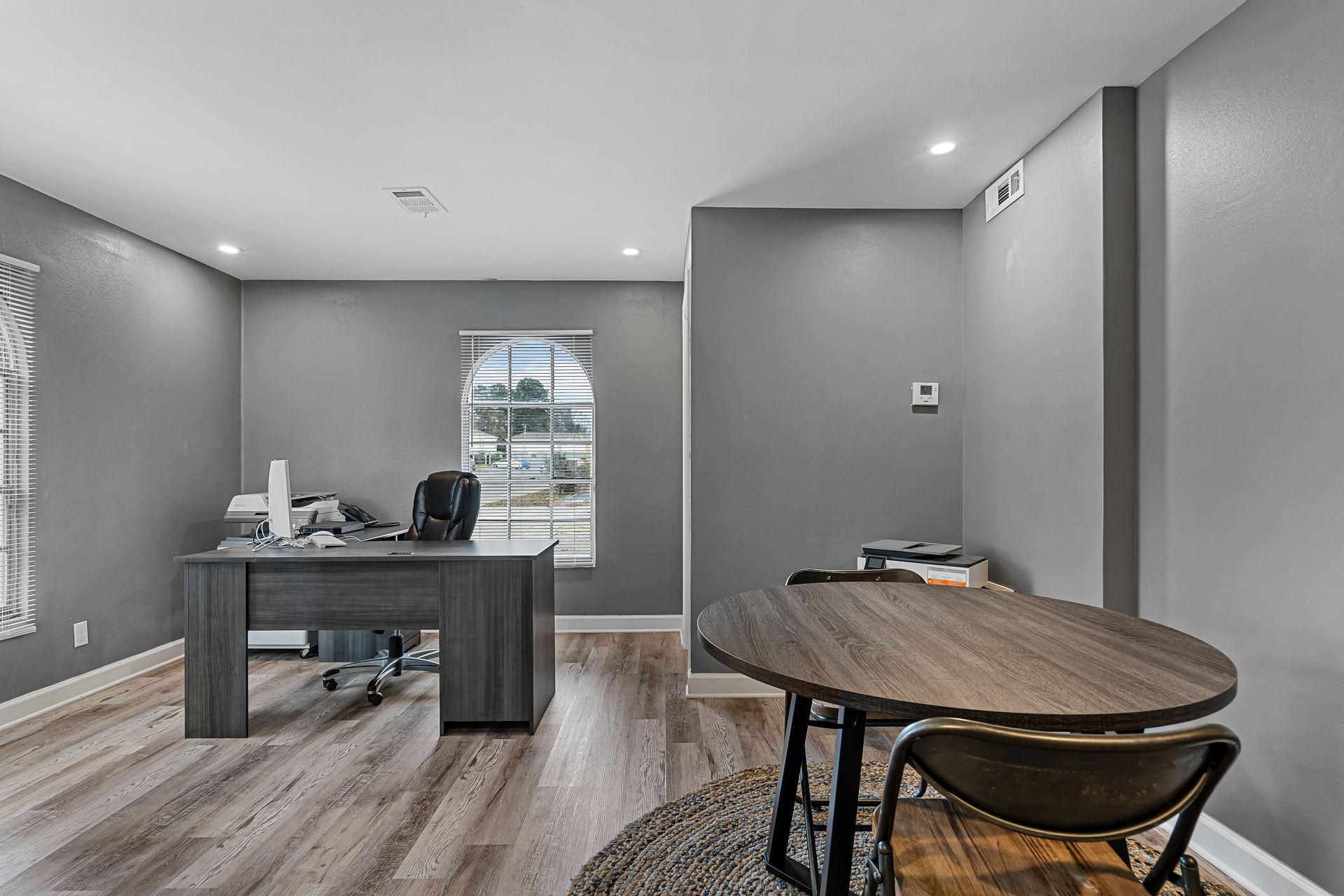 Modern gray home office with desk, chair, window, and round table on rug