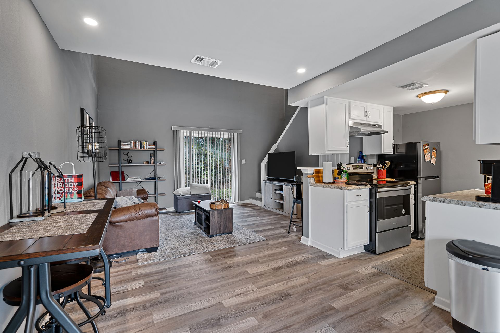 Open-concept living room and kitchen with gray walls, wood floors, and white cabinets