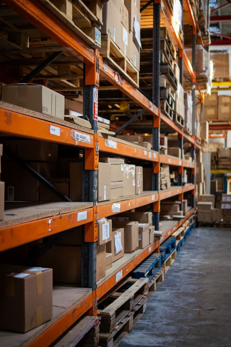 Rows of cardboard boxes on orange warehouse shelves.