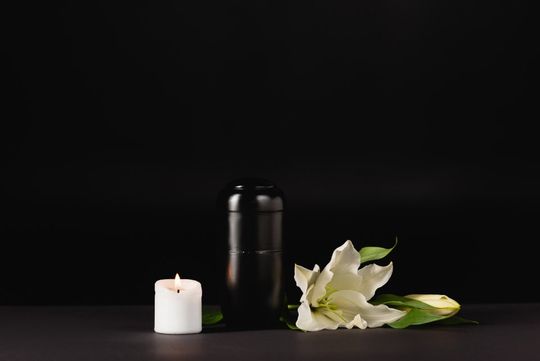 Urna cineraria, fiori e cero funebre