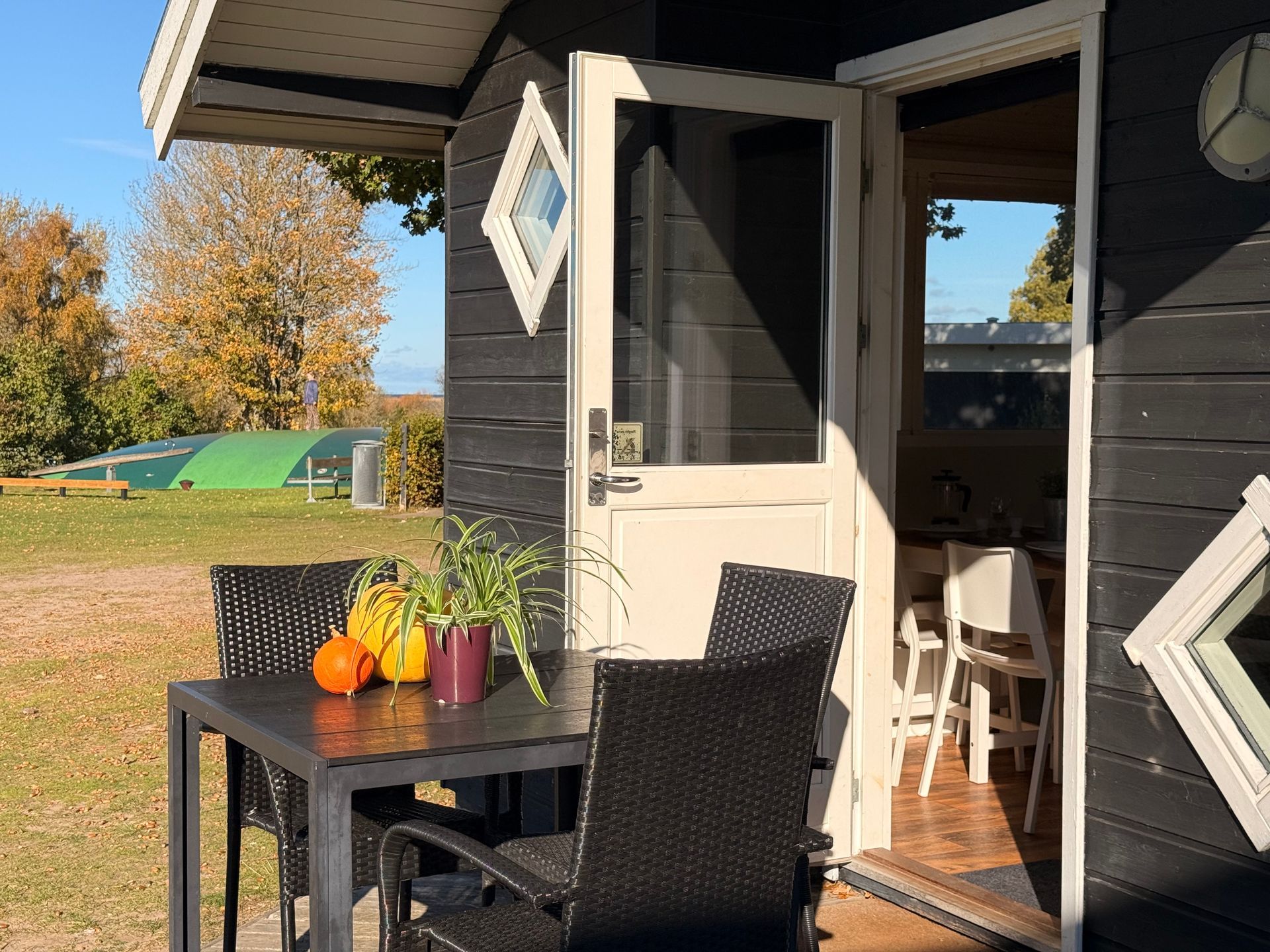 Indgang og terrasse foran en hyggelig hytte.