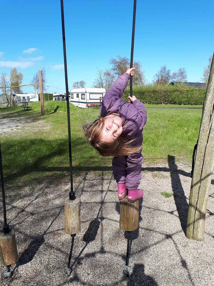 Barn svinger sig i svævebane på naturlegepladsen.