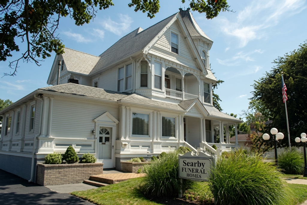 Victorian-style white inn with porch and garden sign on a sunny day