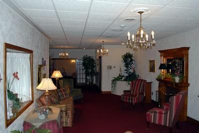Elegant hotel lobby with red carpet, chandeliers, striped armchairs, and a large wall mirror