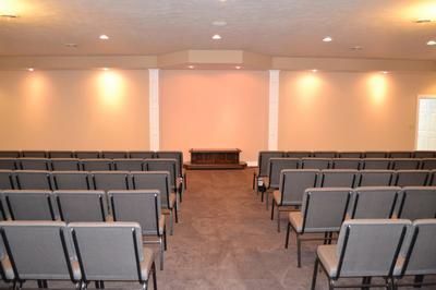 Empty conference room with rows of gray chairs facing a small table at the front
