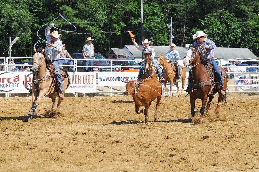 A group of men riding horses in a dirt arena with a sign that says water out