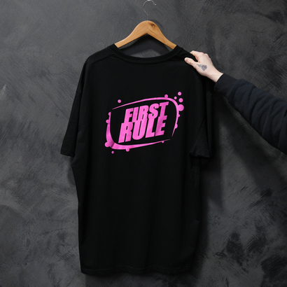 Black T-shirt on a hanger with pink “FIRST RULE” text graphic