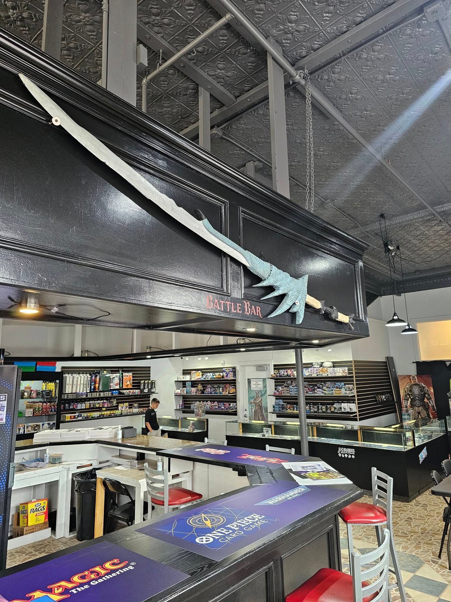 A sword decorates a store, with shelves of products and a bar in the foreground.