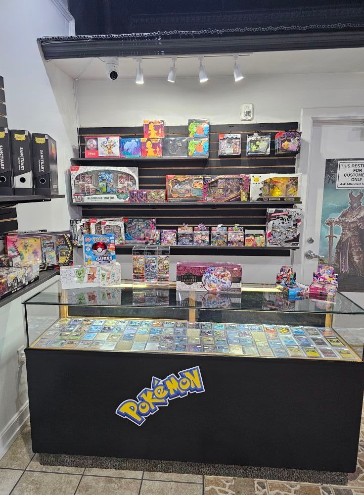 A Pokémon card shop display. Cards are visible in a glass case, boxes are displayed on shelves.