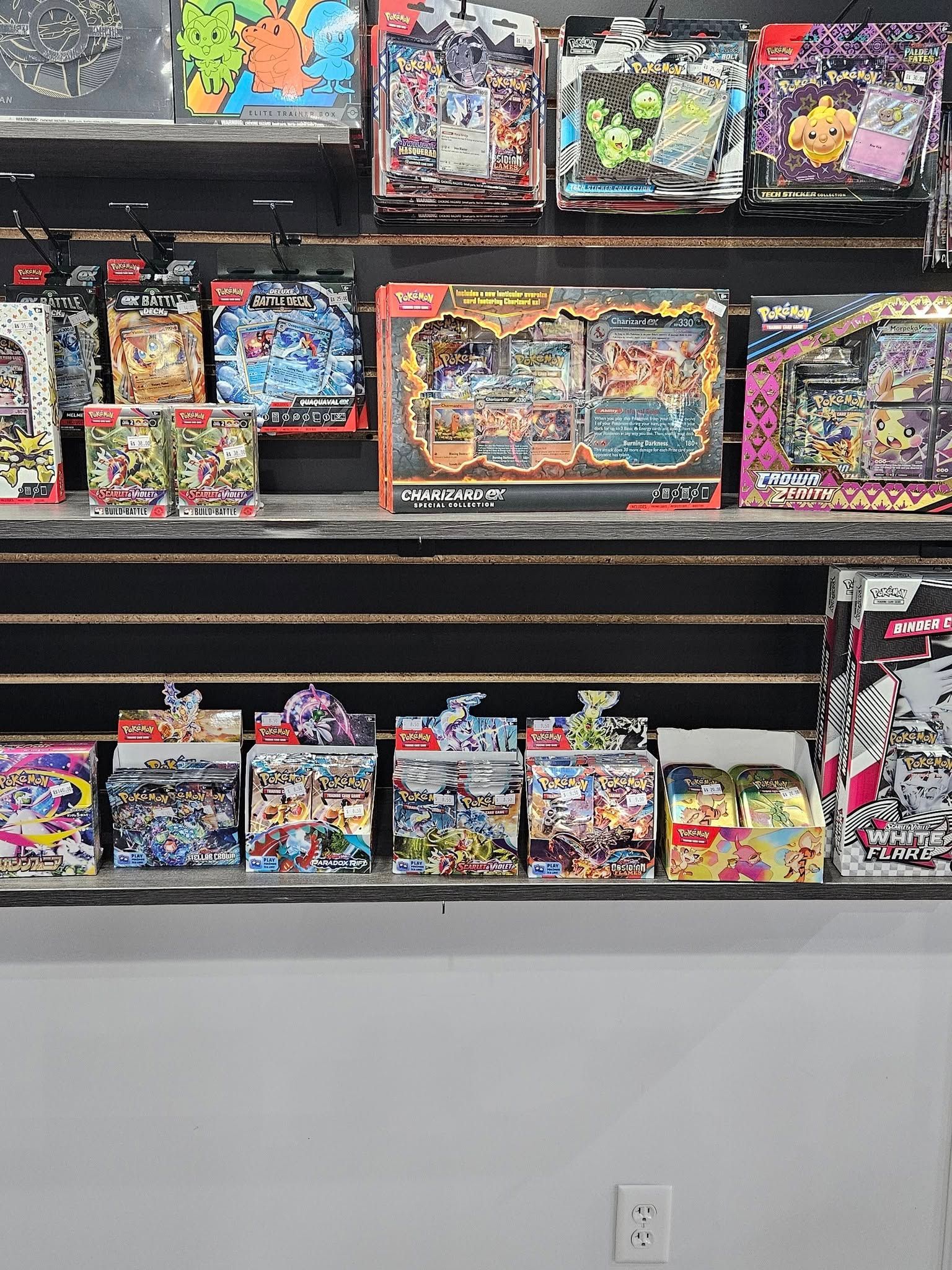Shelves stocked with colorful trading card game boxes and sets at a retail store.