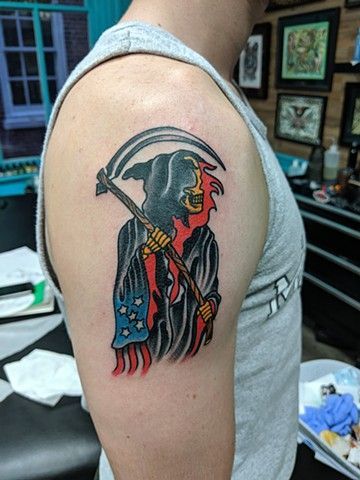 A man has a grim reaper tattoo on his shoulder.