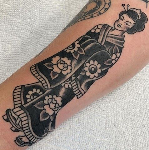 A black and white tattoo of a geisha on a person 's forearm.