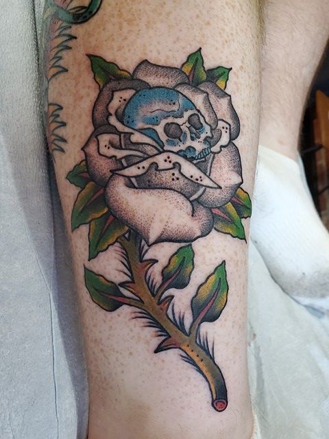 A person has a tattoo of a rose with a skull on it.