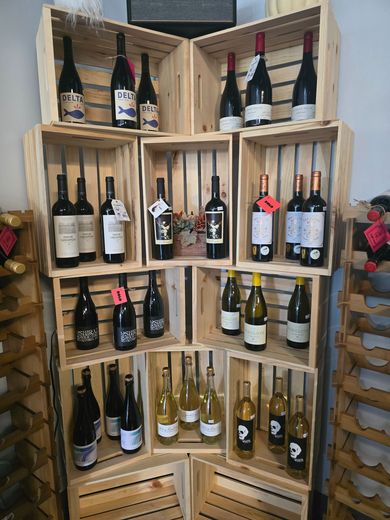 Wooden crate display of assorted wine bottles on shelves in a shop or cellar.