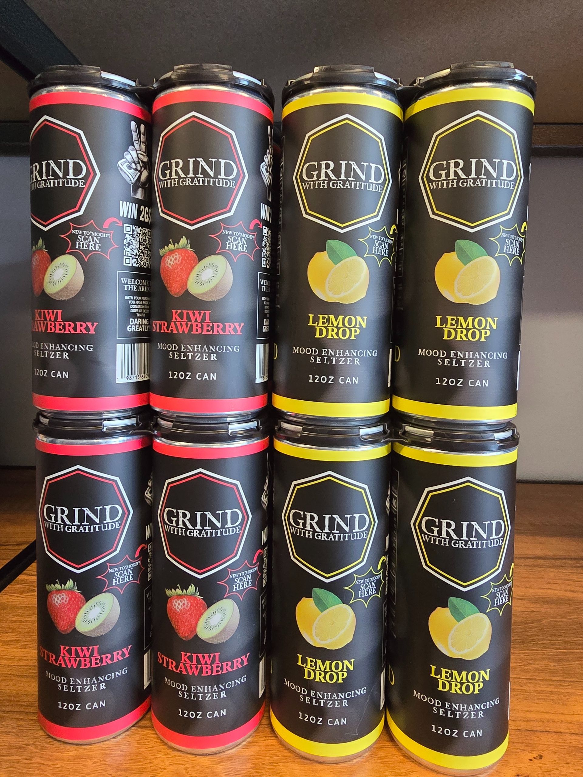 Stacked black-and-red and black-and-yellow GRIND beverage cans displayed in rows.