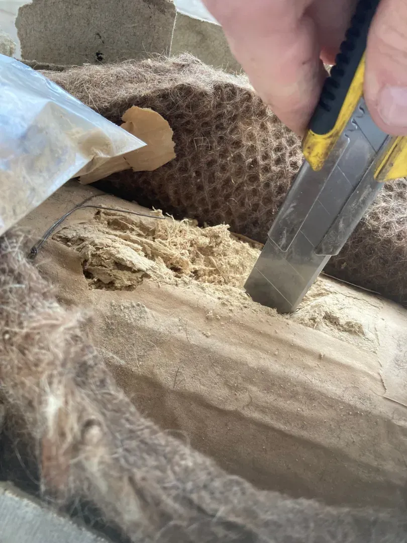 En universalkniv skærer i en blok af komprimeret, fiberholdigt isoleringsmateriale.
