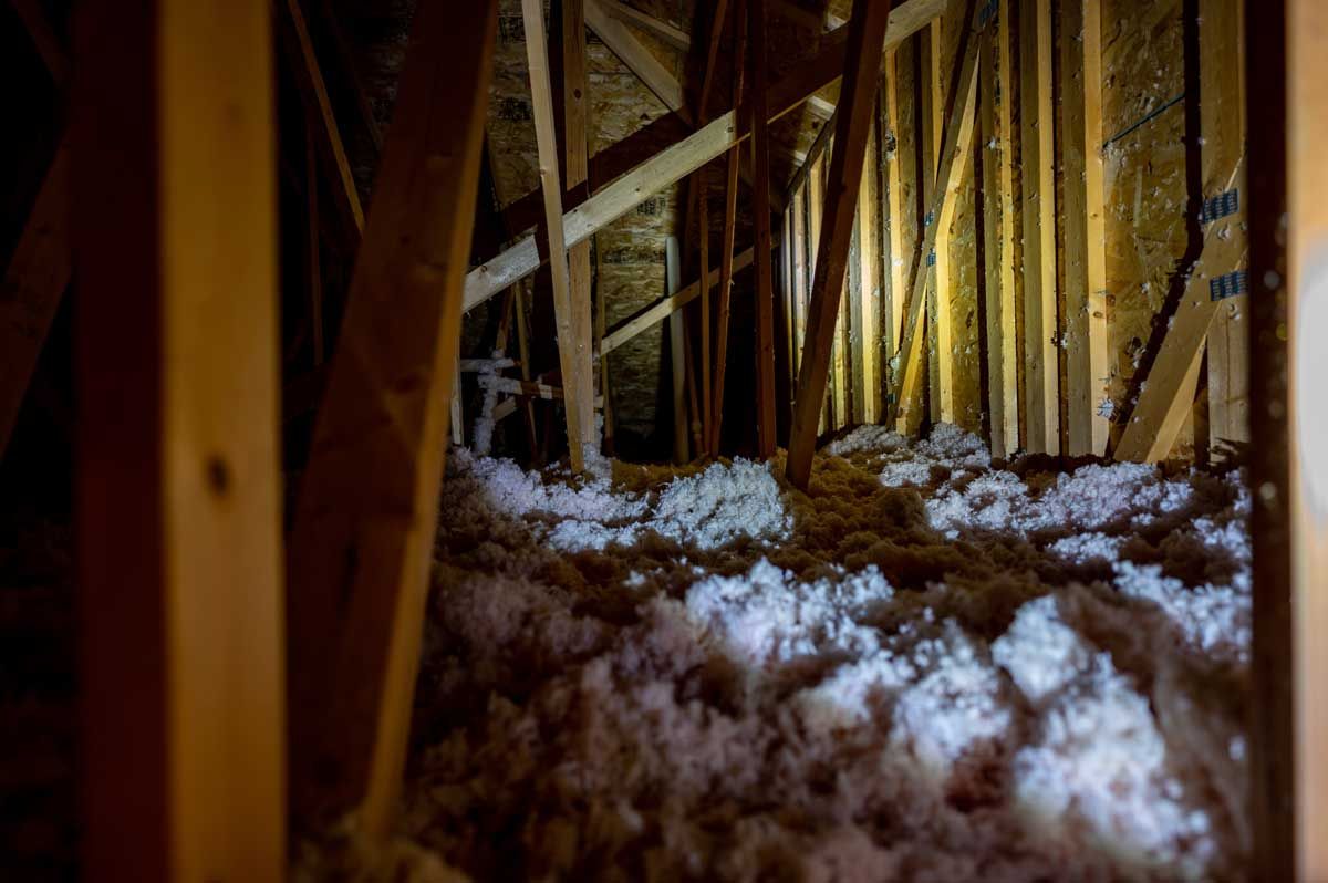 Isoleret loftsrum indrammet af træbjælker og stolper med hvide, gule og brune materialer