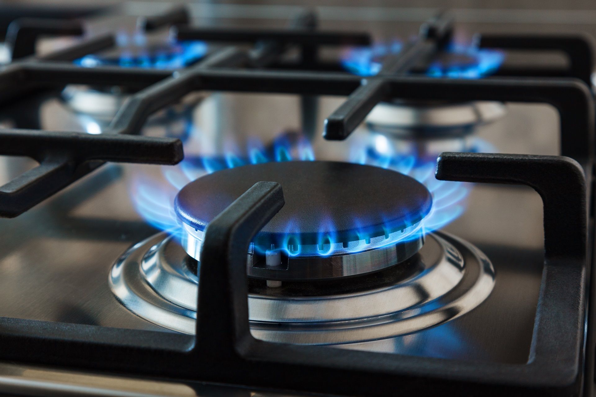 A gloved hand works on a gas meter connection while holding a rubber sealing ring, against a light-colored exterior wall.