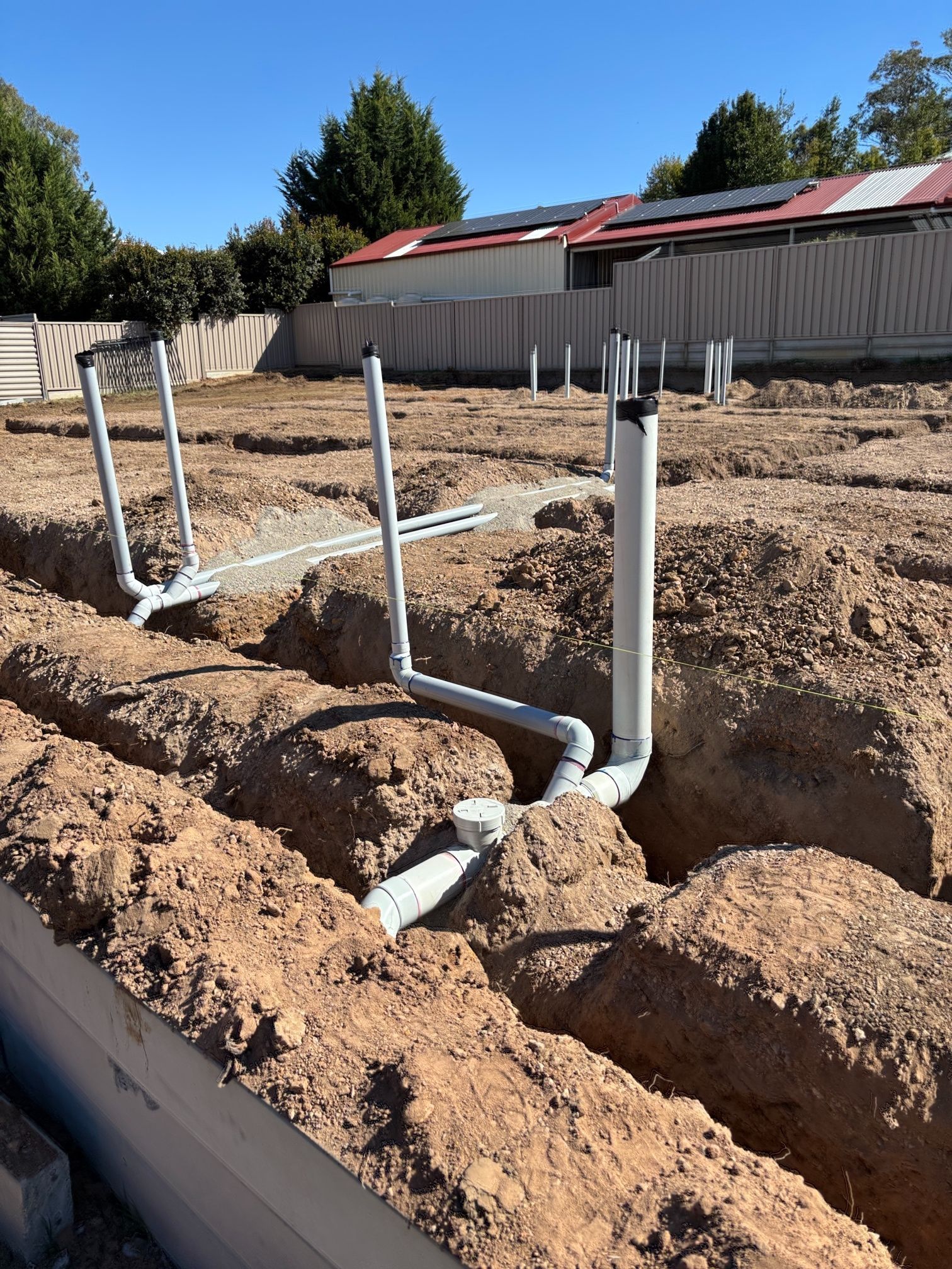 Stormwater runoff flows into a metal storm drain grate on a paved surface.