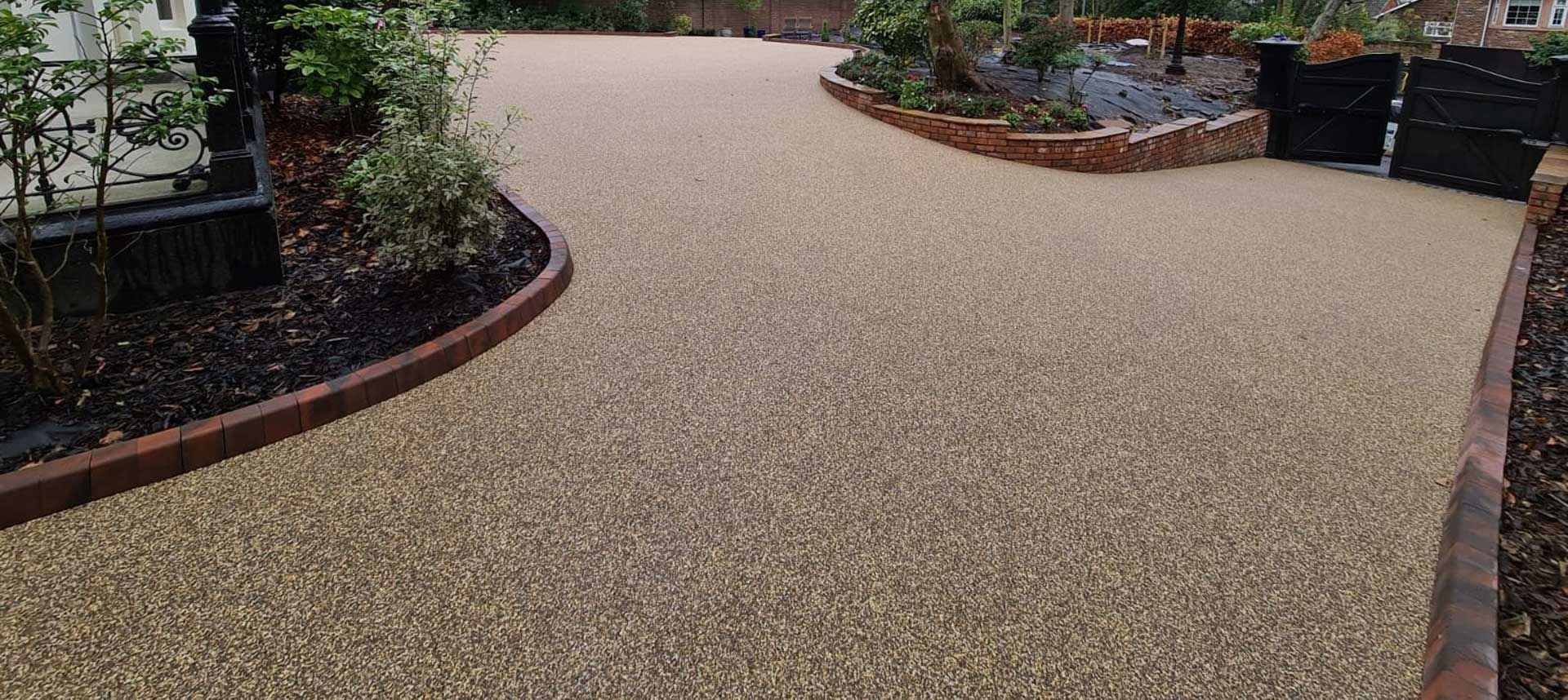 Curved gravel garden path bordered by red brick and planted beds