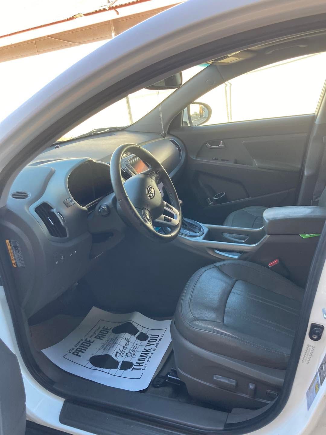Interior of a black car with open driver door, showing the steering wheel and front seats.