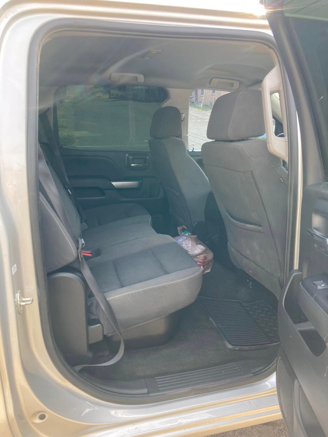Open car rear door showing gray back seats and black floor mat inside the vehicle.