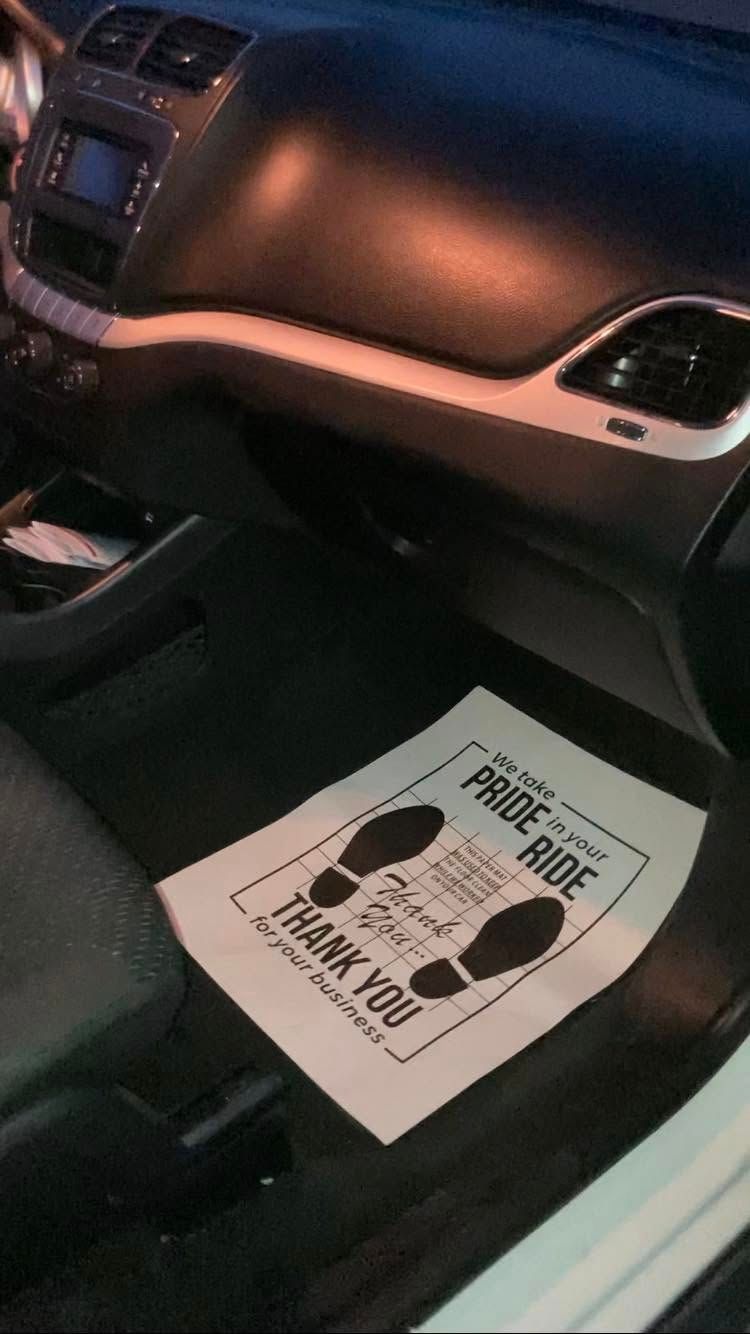 Car floor mat with a graphic warning sign inside a dark vehicle interior