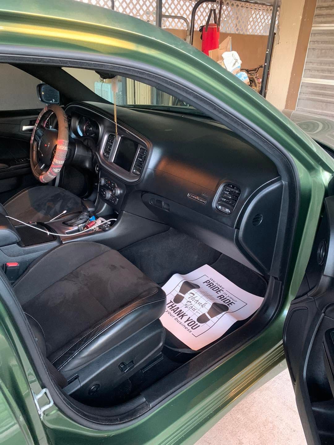 Green car interior with black seats and dashboard, viewed through the open driver’s door