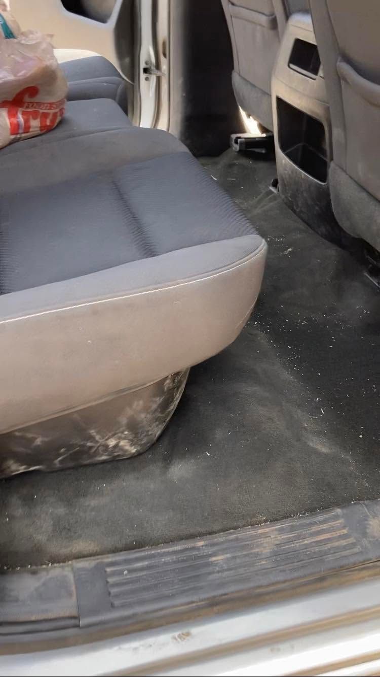 Car interior with gray seats and a black floor mat, viewed from the rear door