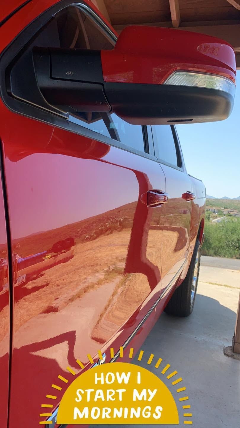 Close-up of a red car’s side mirror and door with a “How I Start My Mornings” sticker.