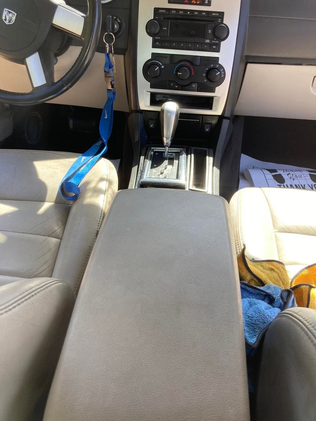 Car interior with beige seats, center console, steering wheel, and blue lanyard hanging near the driver seat.