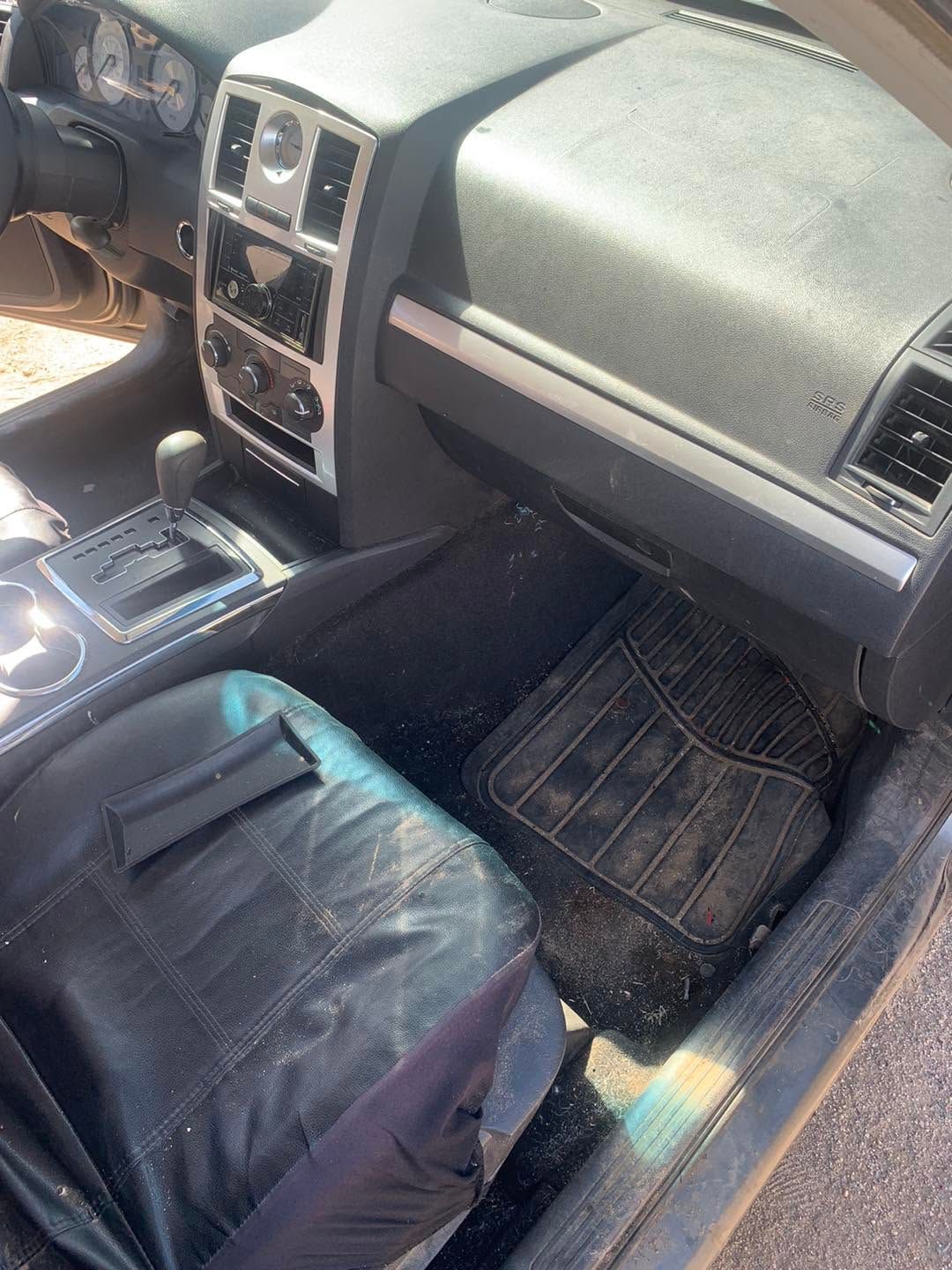 Car interior with black leather seats, center console, and passenger-side floor mat in sunlight