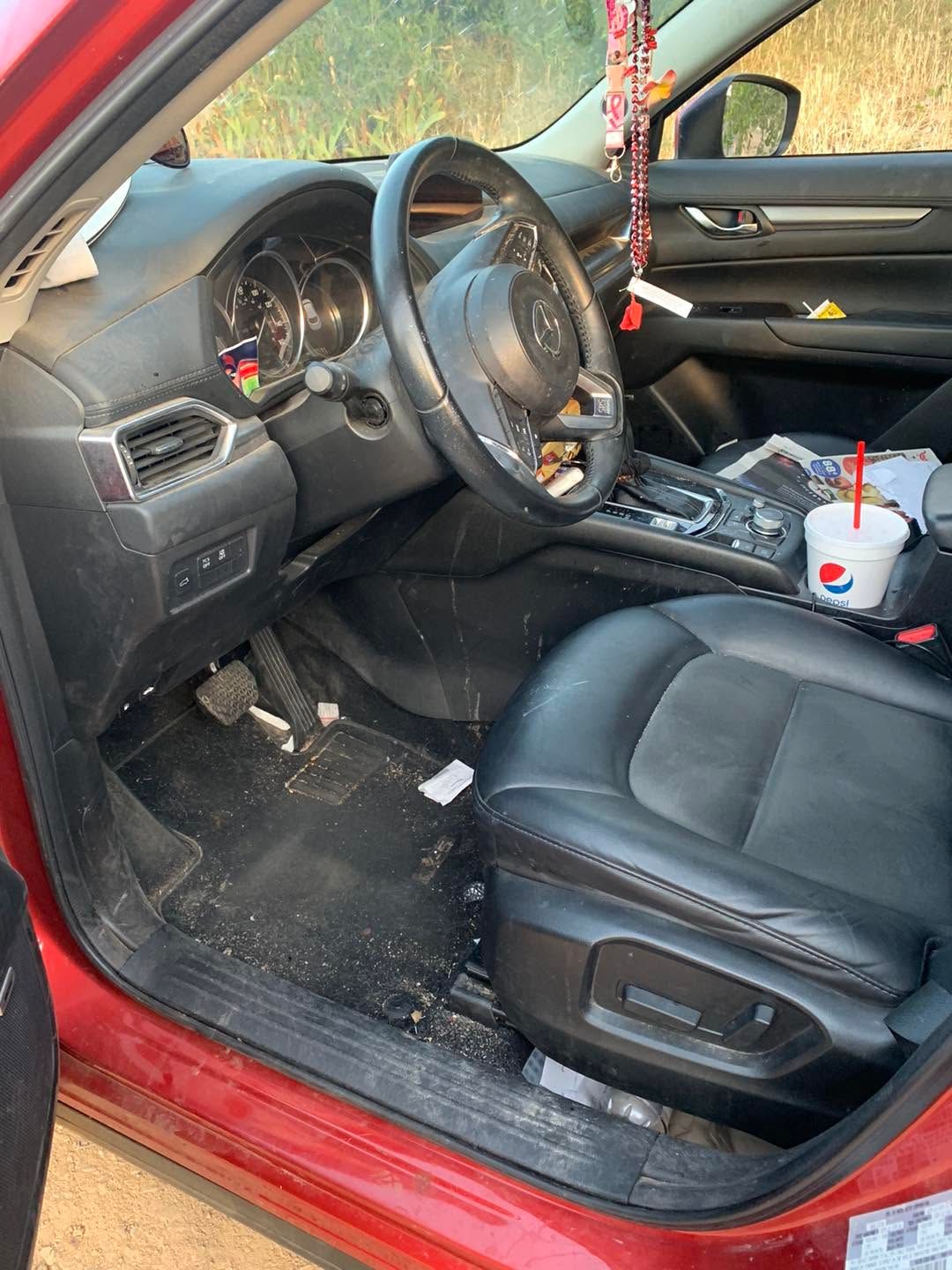 Red car interior with black front seats, steering wheel, and a cup in the center console.