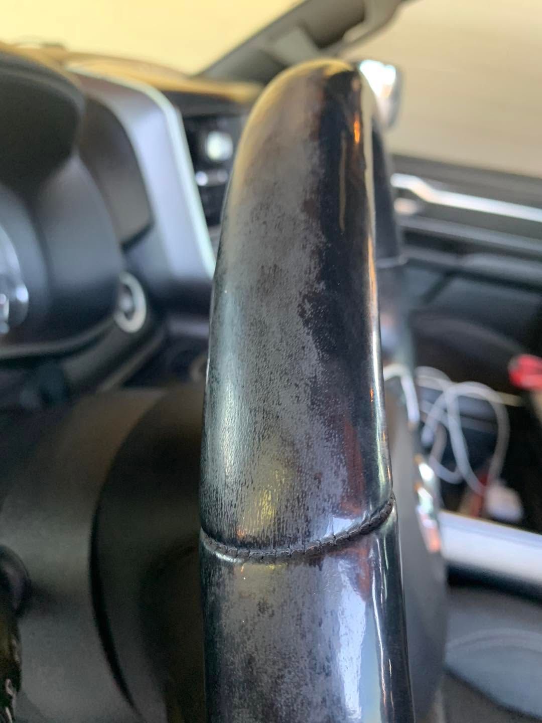 Close-up of a worn black car gear shift knob with the interior blurred in the background