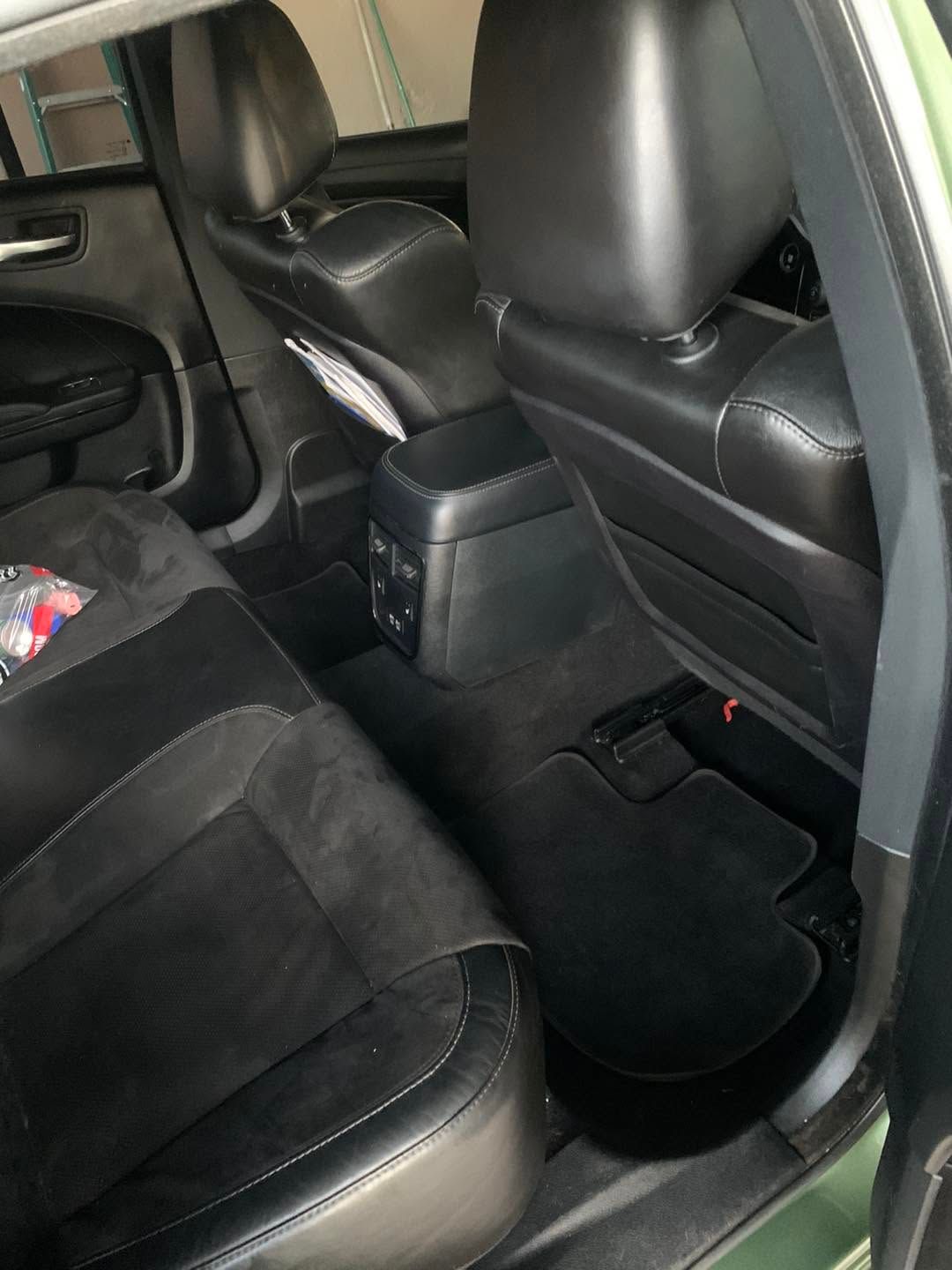 Car interior with black leather seats and a center console, viewed from the rear seat