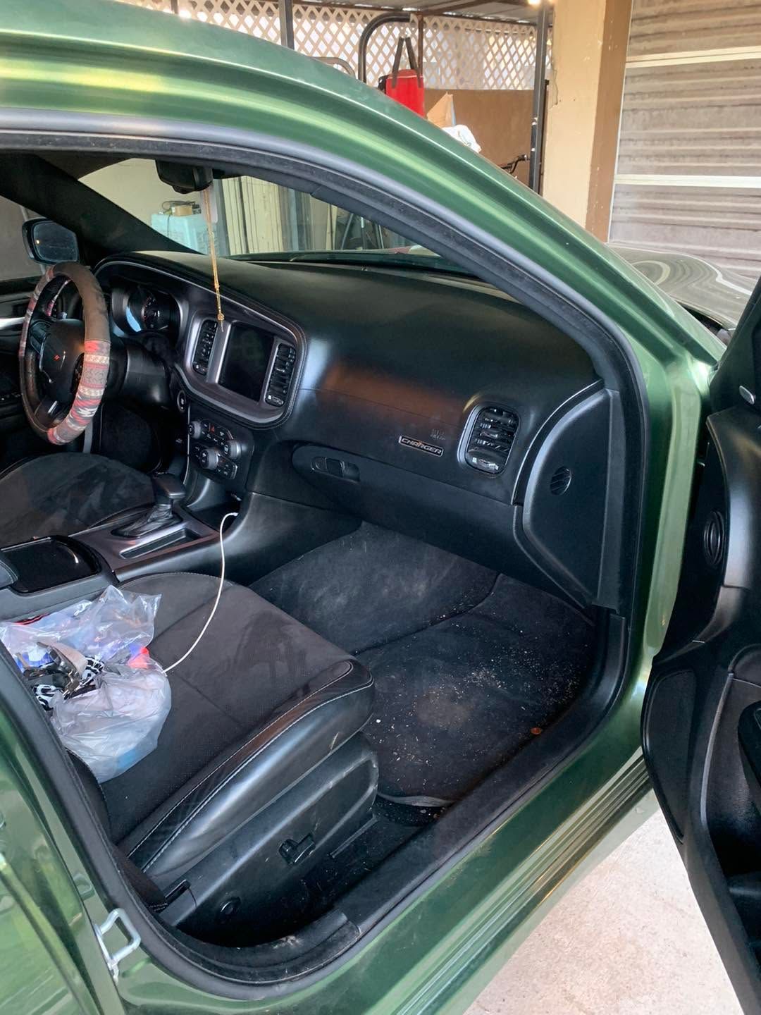 Open green car door revealing a black interior with bucket seats and a dashboard