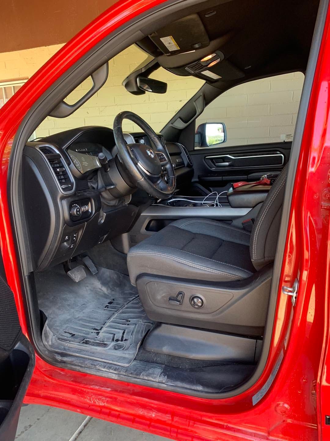 Open red truck door showing black leather driver’s seat and dashboard interior