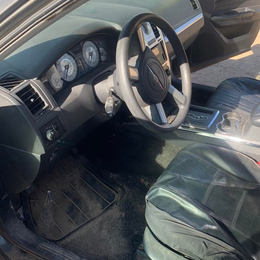 Car interior with black leather seats, steering wheel, dashboard, and center console in daylight.