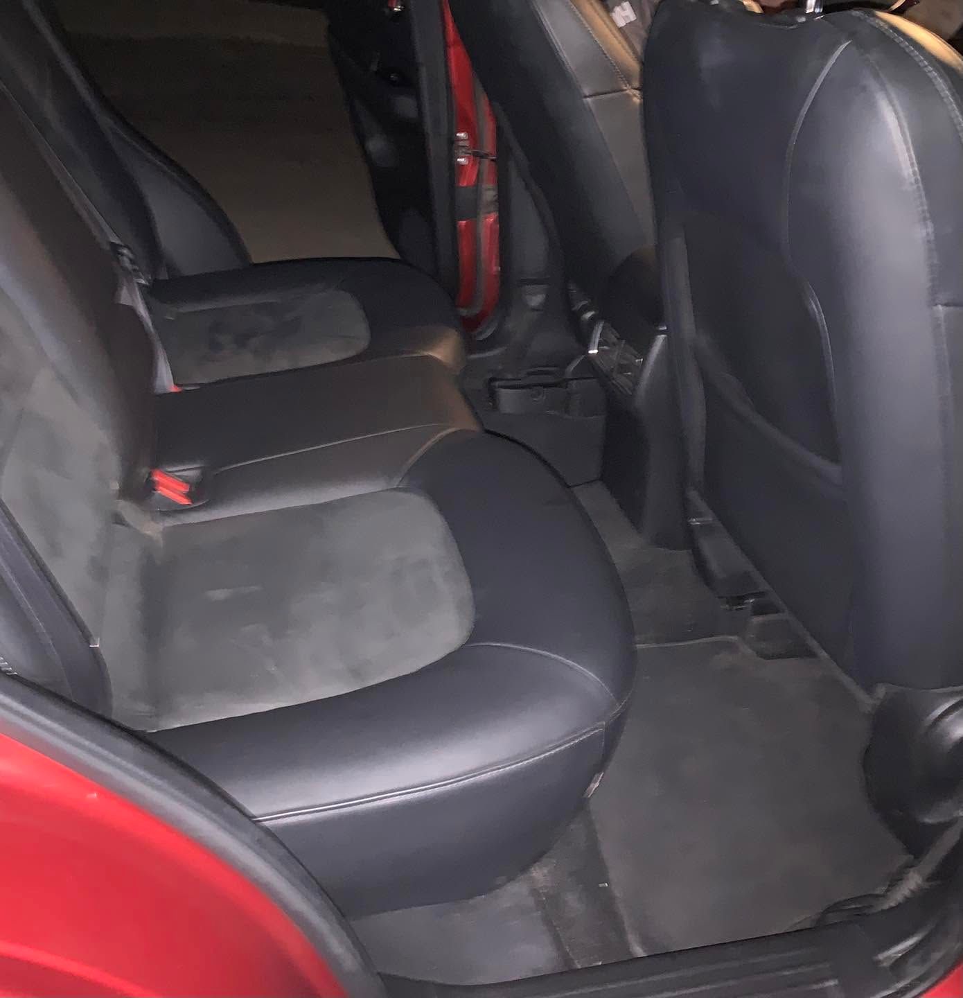 Black car back seat interior with two gray seats and red door frame details