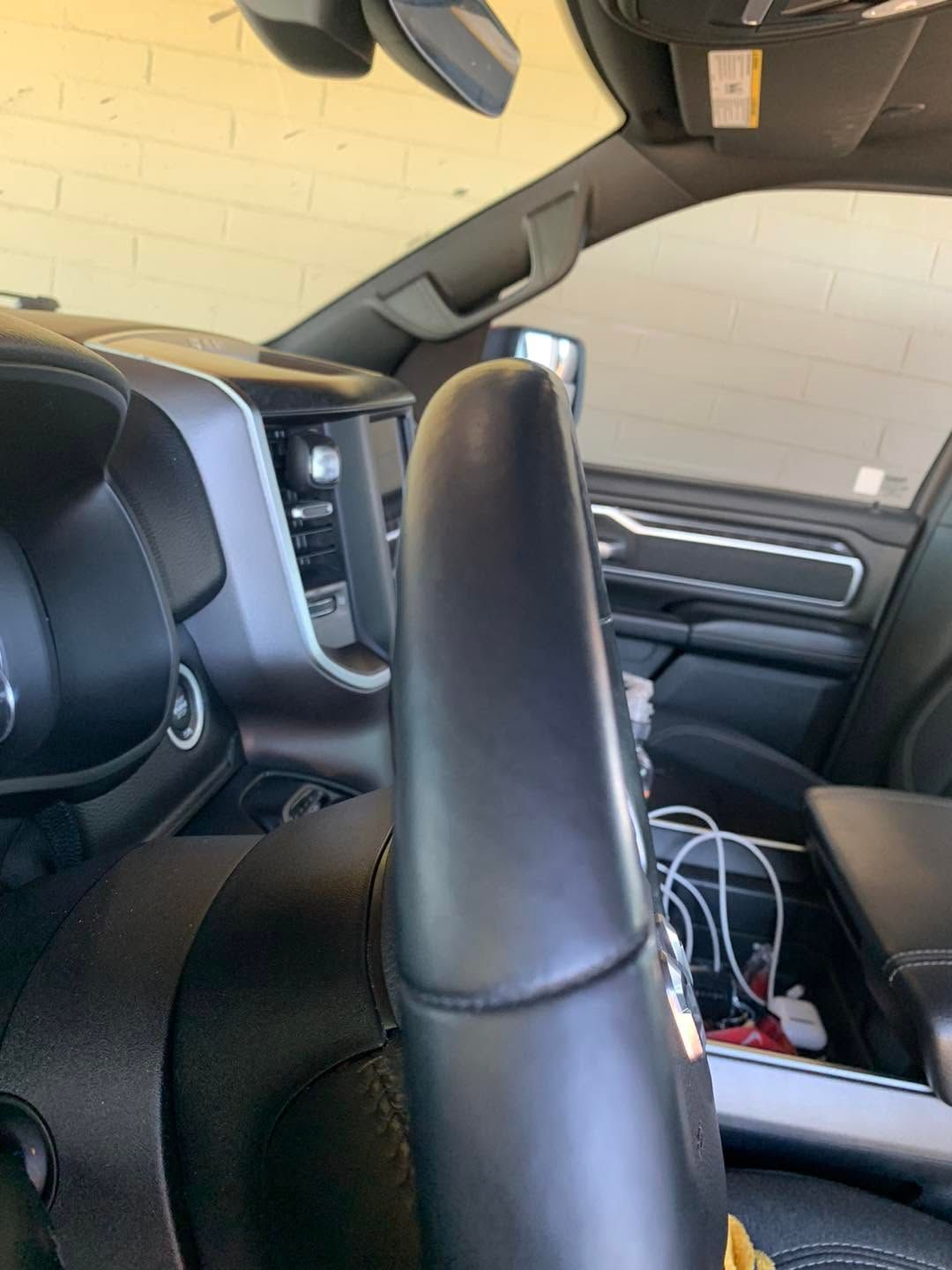 Car interior with black leather seats and a center console holding cables and items.
