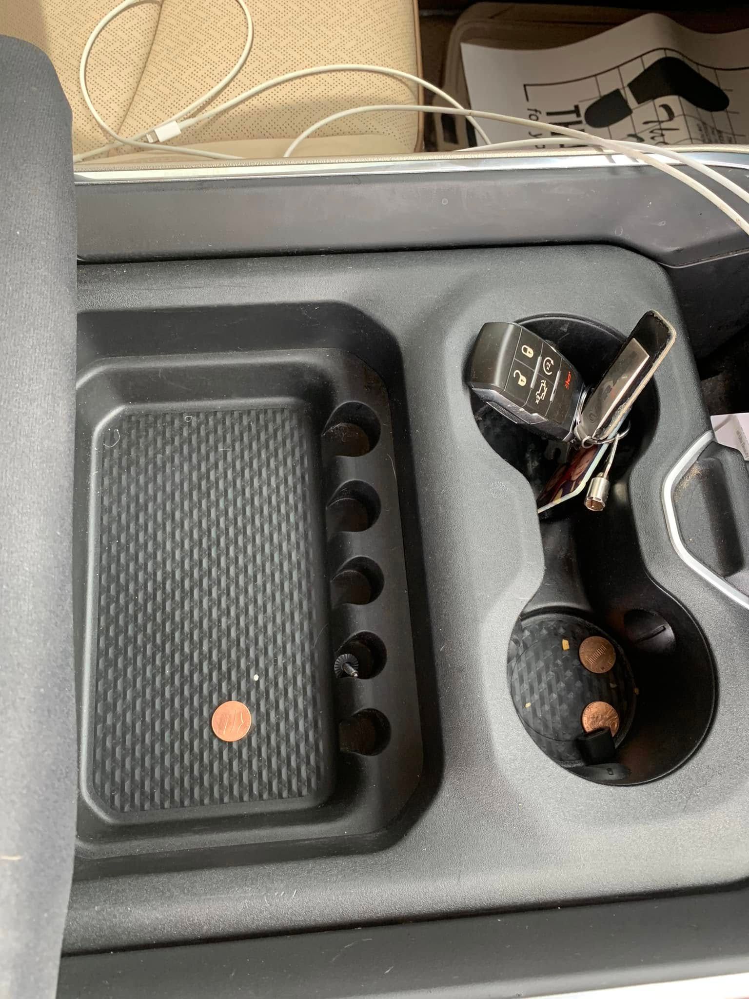 Car organizer tray with sunglasses, a key fob, and small items in gray compartments