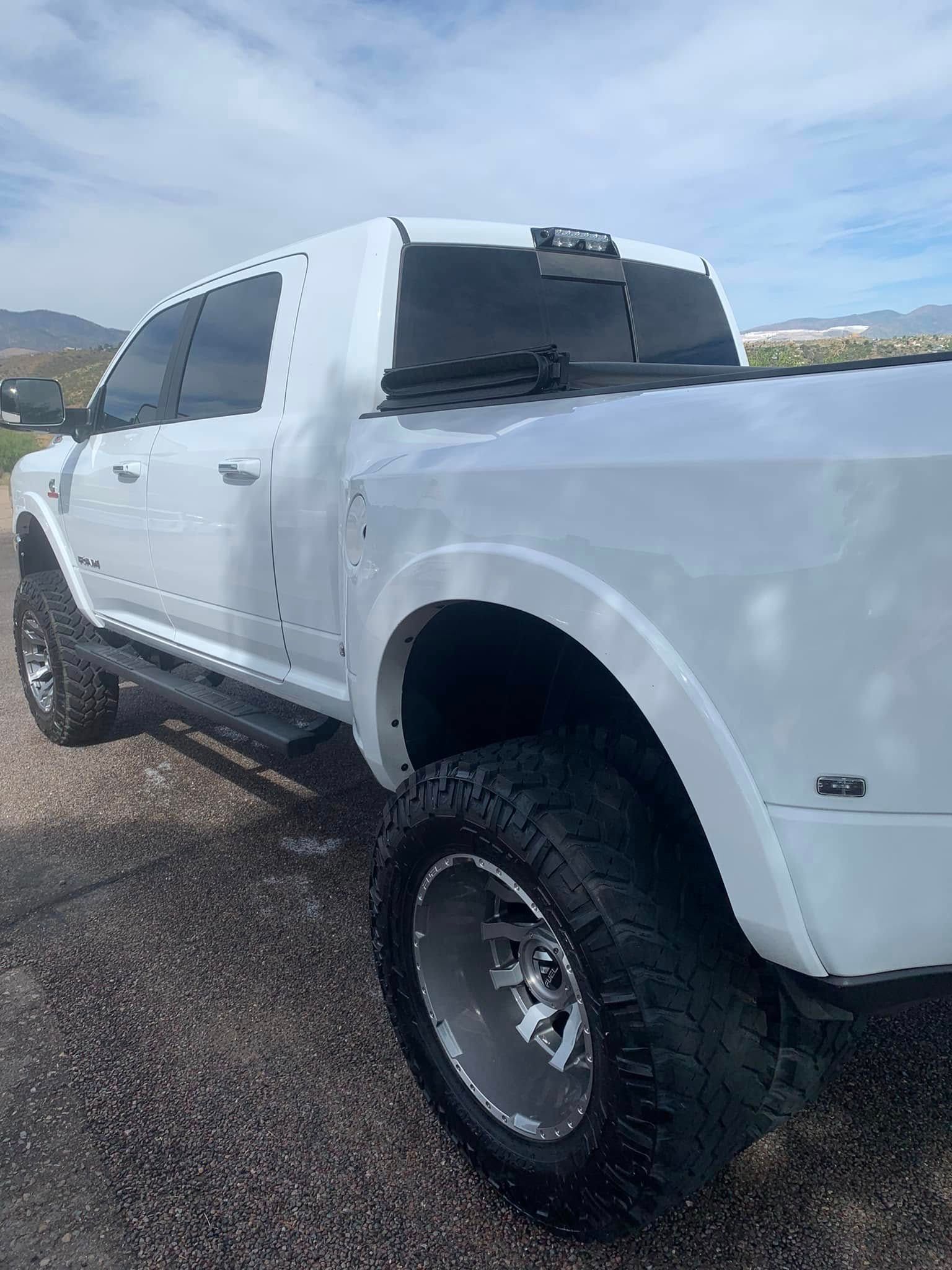 White lifted pickup truck parked on wet pavement under a cloudy sky
